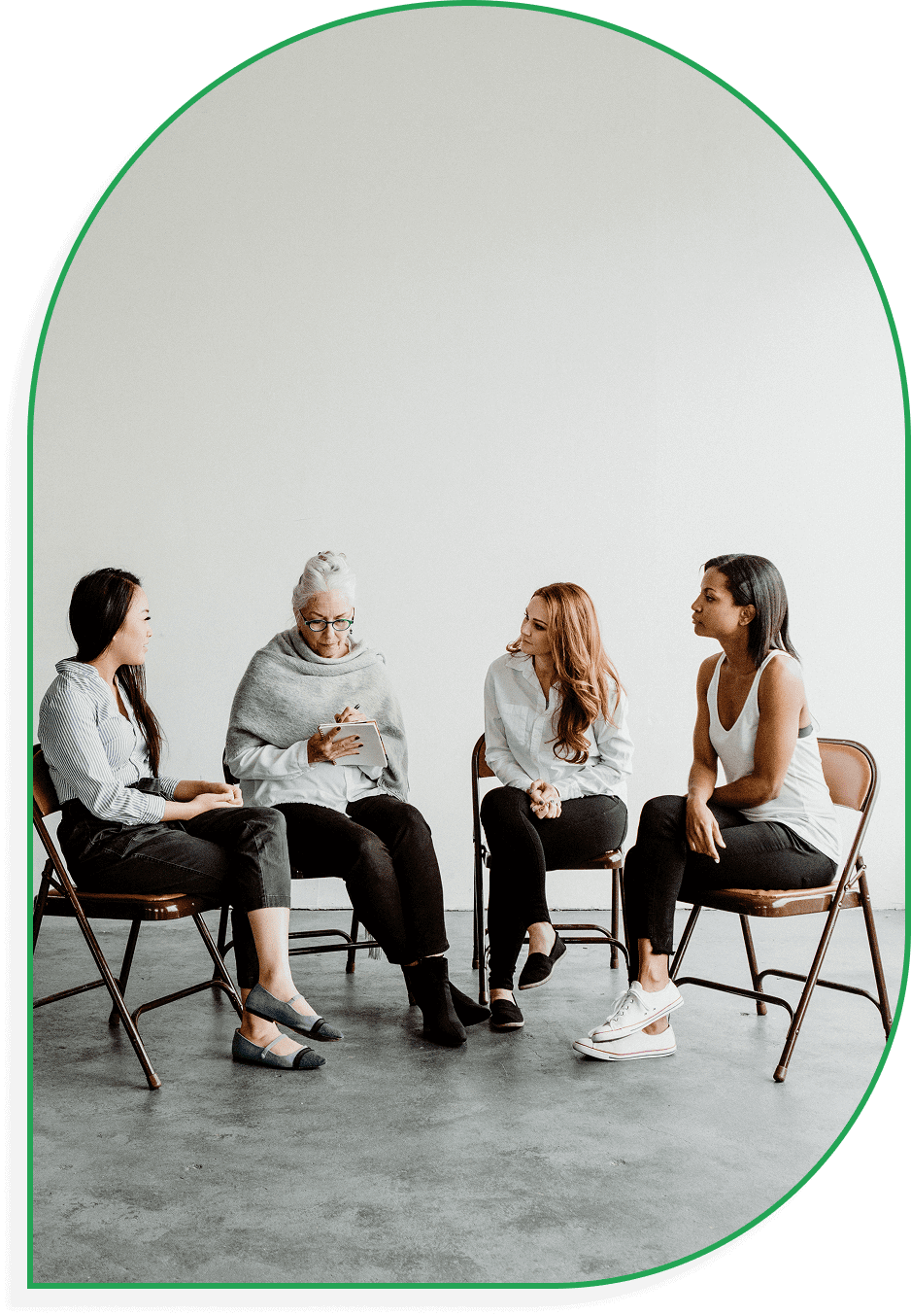 Four women in casual conversation, seated in a minimalistic room.