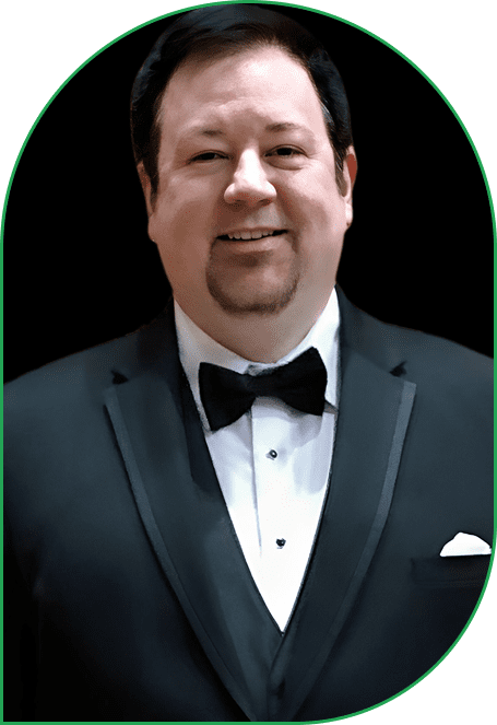 Man in a black tuxedo with a bow tie smiling.