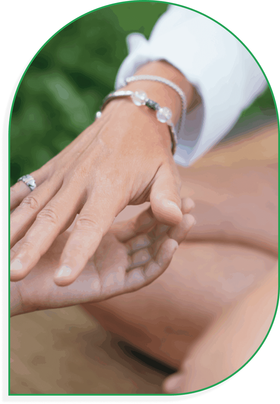 Hands adorned with rings and bracelets gently touching outdoors.